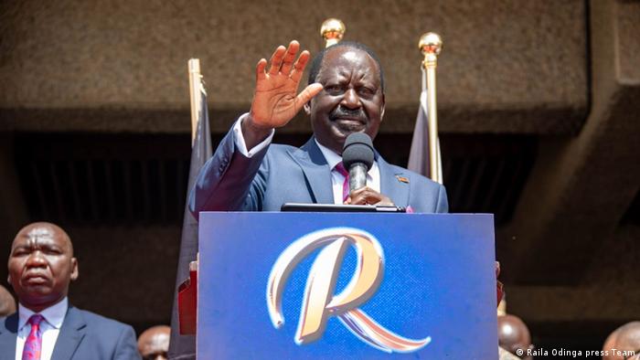 Raila Odinga waves to the crowd from a podium decorated with a giant 'R' for Raila