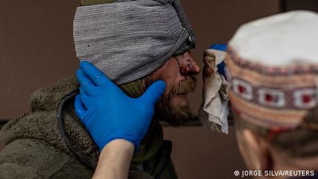 A volunteer medic treats a head wound