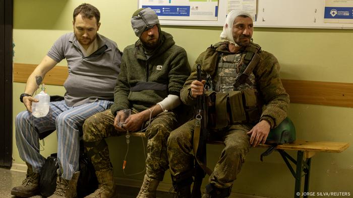 Injured Ukrainian volunteer soldiers sit on a bench and wait for medical treatment