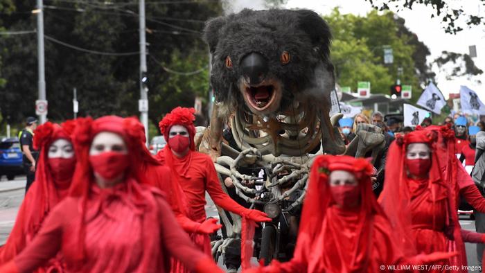 People dressed in red with an art piece depicting a burning koala 