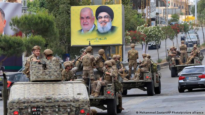 Lebanese army patrol past a poster showing portraits of Hezbollah leader Said Hassan Nasrallah