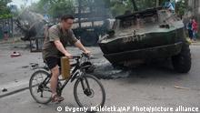 A man rides a bicycle as he passes a site of a battle between Ukrainian troops and pro-Russian fighters in Mariupol, eastern Ukraine, Friday, June 13, 2014. Ukraine¿s interior minister says that government troops have attacked pro-Russian separatists in the southern port of Mariupol. Arsen Avakov said Friday that four government troops were wounded as forces retook buildings occupied by the rebels in the center of the town. (AP Photo/Evgeniy Maloletka)