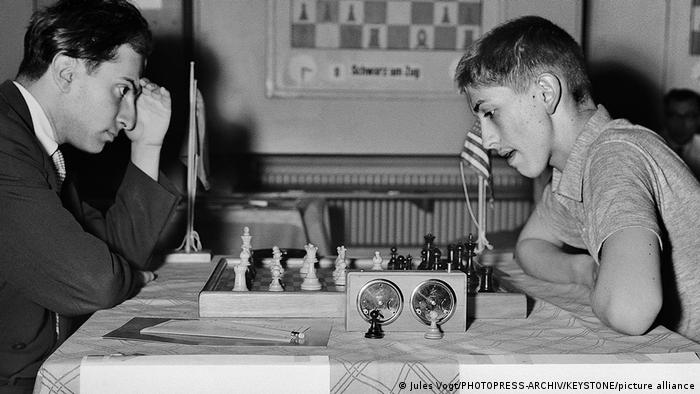 Michail Tal und Bobby Fischer sitzen sich 1959 am Schachtisch gegenüber. Beide gucken nachdenklich aufs Schachfeld. 