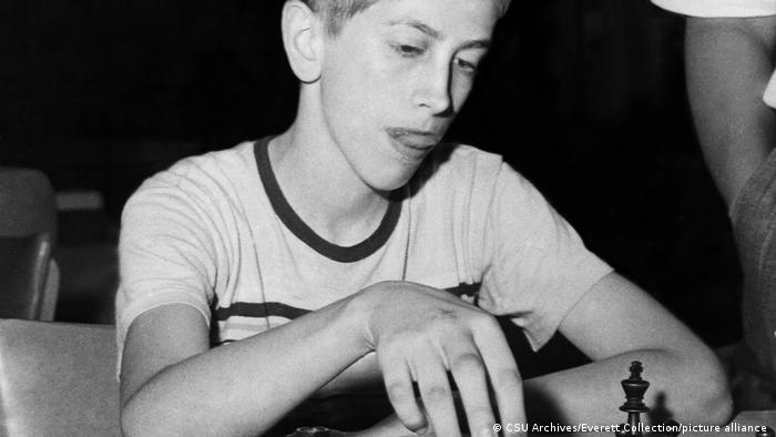 Schwarz-weiß-Aufnahme von Bobby Fischer, der Jugendlicher ist und Schach spielt. 