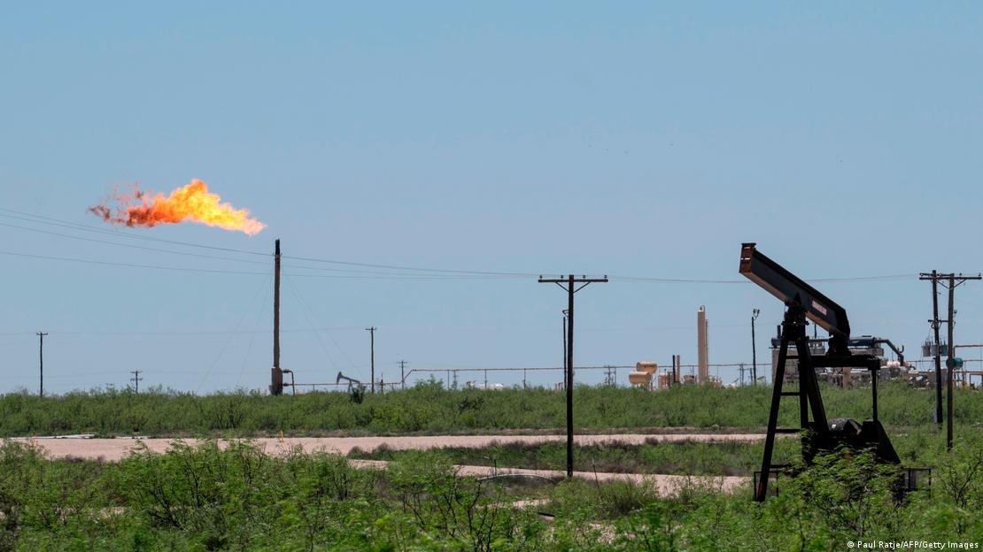 Flare stack is pictured next to pump jacks and other oil and gas infrastructure 