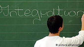 A man writes the word 'integration' on a chalk board