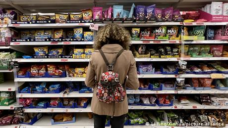 A woman looks at products on a supermarket shelf