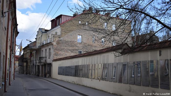 Metallplaketten mit der Verfassung von Uzupis hängen an einer langen Wand in einer Straße in Vilnius
