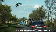 A Russian military helicopter flies over buses with Ukrainian servicemen evacuated from the besieged Mariupol's Azovstal steel plant traveling to a prison in Olyonivka, territory under the government of the Donetsk People's Republic, eastern Ukraine, Tuesday, May 17, 2022. More than 260 fighters, some severely wounded, were pulled from a steel plant on Monday that is the last redoubt of Ukrainian fighters in the city and transported to two towns controlled by separatists, officials on both sides said. (AP Photo/Alexei Alexandrov)