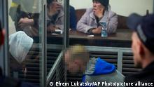 Sitting behind a glass, Russian army Sergeant Vadim Shishimarin, 21, talks with his translator, left, during a court hearing in Kyiv, Ukraine, Wednesday, May 18, 2022. The Russian soldier has gone on trial in Ukraine for the killing of an unarmed civilian. The case that opened in Kyiv marked the first time a member of the Russian military has been prosecuted for a war crime since Russia invaded Ukraine 11 weeks ago. (AP Photo/Efrem Lukatsky)