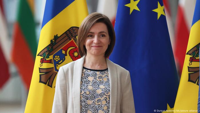 Moldovan President Maia Sandu standing in front of a flag