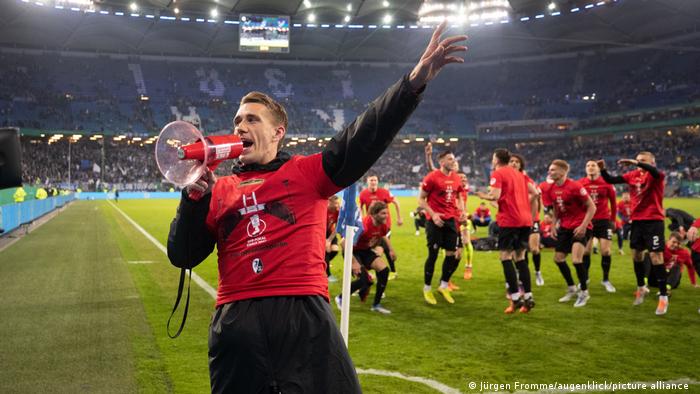 Freiburg's Nils Petersen leads the celebrations with a megaphone after Freiburg's semifinal win over Hamburg