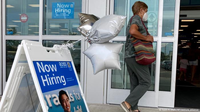 A shopper passing a hiring sign outside a shop