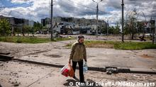 TOPSHOT - A woman carries bags with food while she walks in the Saltivka district, northern Kharkiv, on May 17, 2022, on the 83rd day of the Russian invasion of Ukraine. - Ukraine said on late May 15, 2022 its troops have regained control of territory on the Russian border near the country's second-largest city of Kharkiv, which has been under constant fire since Moscow's invasion began. (Photo by Dimitar DILKOFF / AFP) (Photo by DIMITAR DILKOFF/AFP via Getty Images)