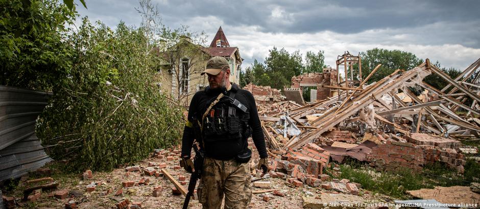 A Ukrainian territory defence soldier walks past the ruins of a building in Donbas