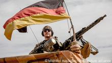 13 November 2018, Mali, Gao: A soldier of the Bundeswehr is standing next to his machine gun at the airport near the base in Gao in northern Mali. The German Defence Minister von der Leyen visited the German soldiers in northeastern Mali on the third day of her trip to West Africa. The CDU politician visited the Camp Castor in Gao, where most of the German contingent of the UN troop Minusma is stationed. Photo: Michael Kappeler/dpa