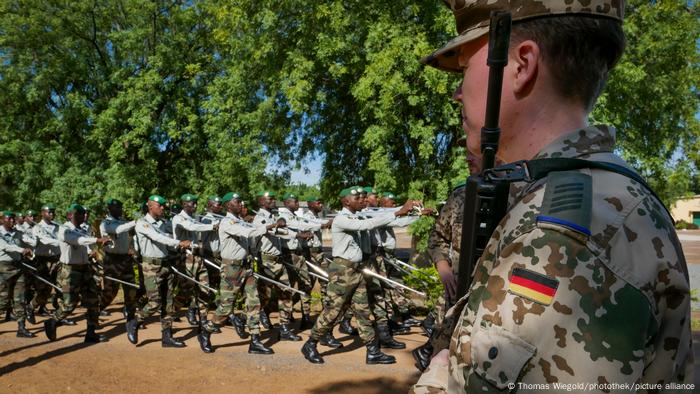 A German soldier watches on as security forces march at the EU's Koulikoro Training Center in Mali.