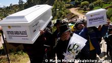 Residents carry white coffins while a man wipes away tears while carrrying white flowers up a road