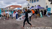 A surfer runs past a polling booth in Sydney, Australia. (AP Photo/Mark Baker)