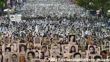 Portraits of people who disappeared during the last dictatorship (1973-1985) in Uruguay are held by people taking part in the Marcha del Silencio (March of Silence) in Montevideo, on May 20, 2022. (Photo by PABLO PORCIUNCULA / AFP) (Photo by PABLO PORCIUNCULA/AFP via Getty Images)