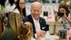 Biden smiles while sitting at a table with a woman holding a little girl in her lap Biden smiles while sitting at a table with a woman holding a little girl in her lap