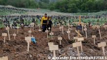 People stand amid newly-made graves at a cemetery in the course of Ukraine-Russia conflict in the settlement of Staryi Krym outside Mariupol, Ukraine May 22, 2022. REUTERS/Alexander Ermochenko TPX IMAGES OF THE DAY 