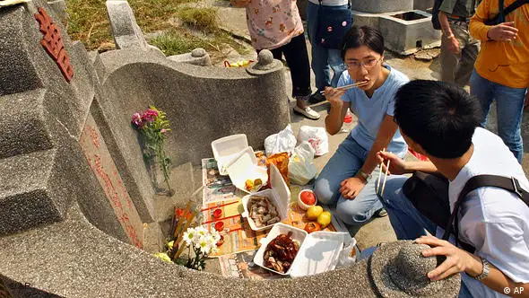 Kitty Li, 23, seated on the ground in center, talks to her brother Ryan Li, 21, right, while sharing some of the food offerings to the deceased at their ancestors' grave at the Diamond Hill cemetery in Hong Kong, Friday, Oct. 22, 2004. Hong Kong people went out on Friday, to clean and sweep their ancestors' graves, a tradition for the Chung Yeung Festival that shows respect for the dead. The festival is a public holiday in Hong Kong. (AP Photo/Anat Givon)