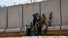 Camp children play on the wall separating Syria and Turkey near the town of Atma in Idlib countryside, northwest of Syria, on May 17, 2022. (Photo by Rami Alsayed/NurPhoto)