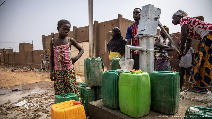 A girl waits her turn at a water pump