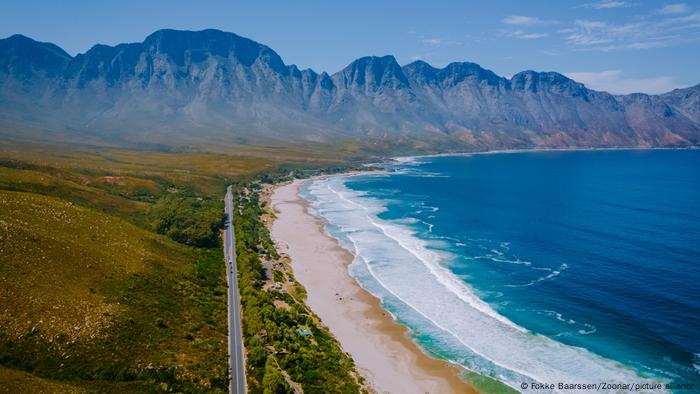 A sweeping view of an ocean and beach, with mountains in the background