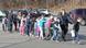 A imagem mostra uma fila de crianças assustadas, junto a professoras e um policial, em um estacionamento próximo à escola onde um atentado com arma de fogo havia ocorrido, em 14 de dezembro de 2012, em Newtown, nos Estados Unidos.