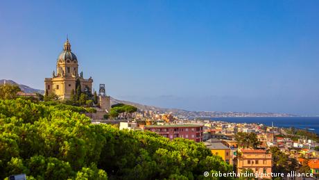 Skyline von Messina mit bunten Häusern und einer Kathedrale. Im Hintergrund ist das Meer.