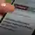 Closeup of a hand holding a smartphone displaying some text in Greek