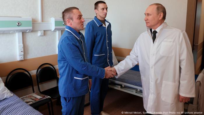 Russian President Vladimir Putin, right, shakes hands with Warrant officer Yuzbeg Kazitov, left, and Sgt. Ivan Petruk, second left, at the Central Military Clinical Hospital in Moscow