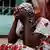 The mother of a ten-day-old baby who died in a fire at a hospital in Tivaouane, Senegal holds her head in her hands while sitting outside the hospital