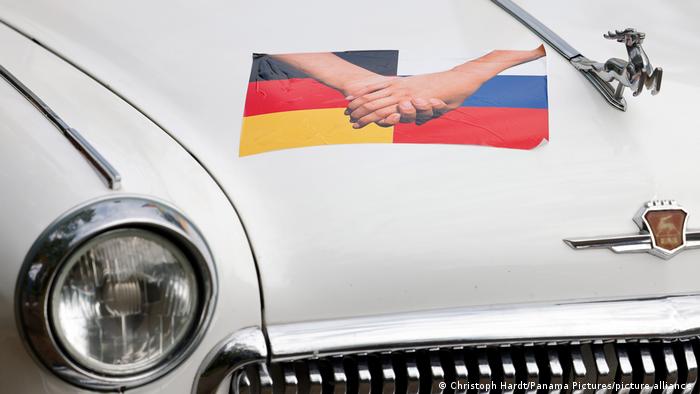 Oldtimer russe avec photo de deux mains tenant ensemble contre un drapeau allemand et un drapeau russe