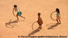 Kinder spielen mit Reifen auf Dorfstraße, Bevato, Distrikt Tsiroanomandidy, Region Bongolava, Madagaskar, Afrika