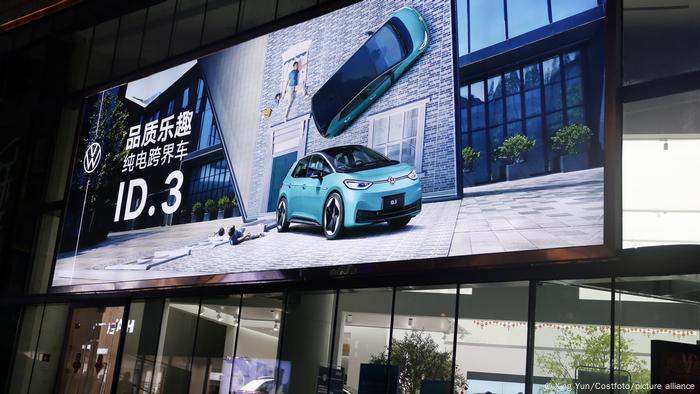 Beleuchtetes VW-Plakat mit Elektroauto ID.3 mit chinesischer Schrift über einem Autohaus