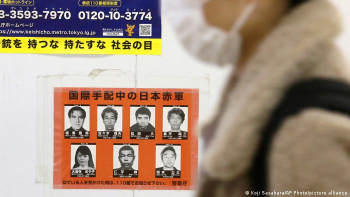 A woman walks past a poster of wanted Japanese terrorists in Tokyo, Tuesday, Feb. 15, 2022. Tokyo police on Monday stepped up the hunt for members of the Japanese Red Army wanted for their alleged role in attacks in the 1970s and 1980s, releasing a video with images of the aging militants that warned the “case” was not over yet.