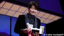 South Korean actor Song Kang-Ho poses on stage with his trophy after he was awarded with the Best Actor Prize for his part in Broker (Les Bonnes Etoiles) during the 75th edition of the Cannes Film Festival in Cannes, southern France, on May 28, 2022. (Photo by Valery HACHE / AFP)