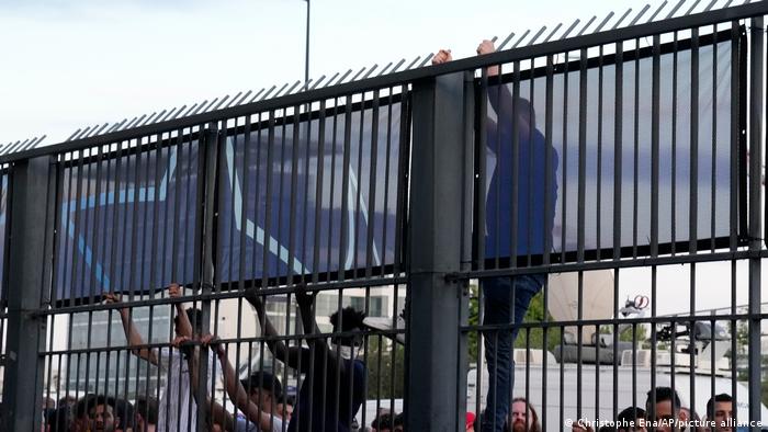 A fan climbs on the fence in front of the Stade de France prior the Champions League final