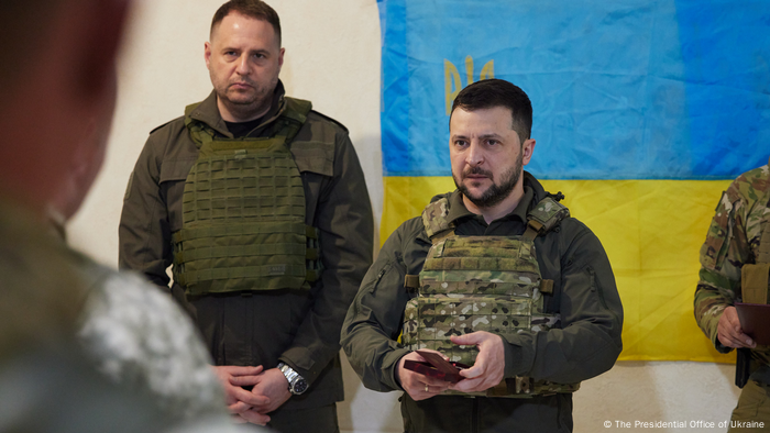 Volodymyr Zelenskyy weaing a bullet-proof vest and standing in front of a Ukrainian flag in Kharkiv