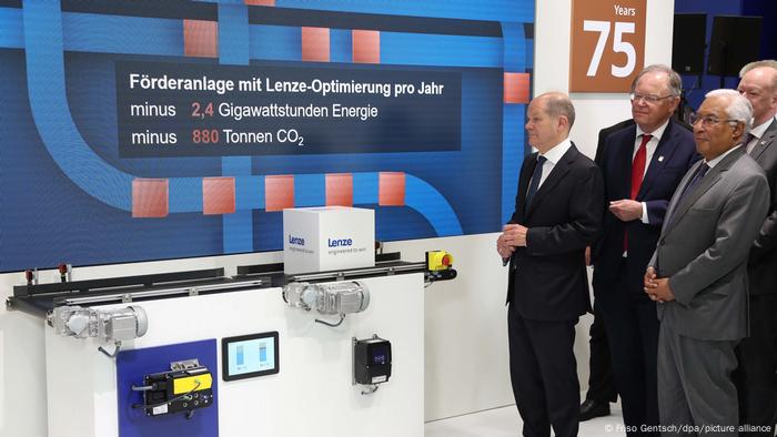 German politicians including Chancellor Olaf Scholz stand in front of an installation at the Hanover trade fair 2022