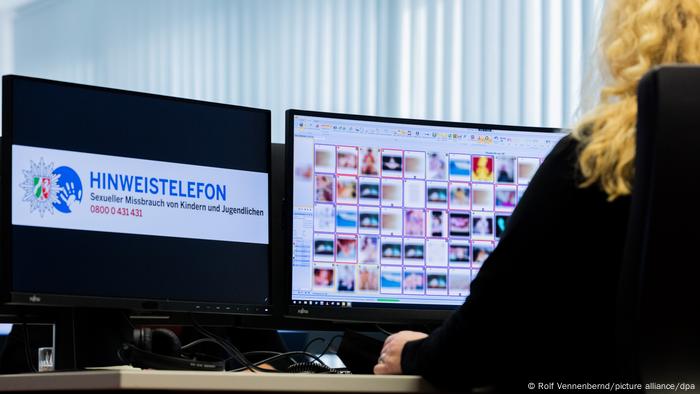 Un oficial de policía mirando una pantalla de computadora que muestra imágenes de abuso infantil (pixeladas)