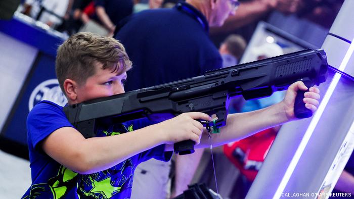 A boy tries out a 12 gauge Smith and Wesson shotgun as people attend the National Rifle Association (NRA) annual convention in Houston, Texas, on May 28, 2022