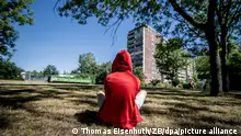 31. Juli 2020: Leipzig (Sachsen), Stadtteil Gruenau: Ein Kind sitzt vor einem Plattenbau in Leipzig-Gruenau. Foto: Thomas Eisenhuth