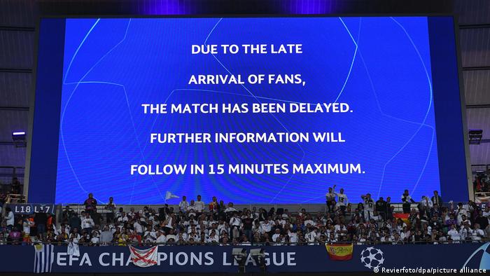 A big screen at the Stade de France shows a message informing spectators about a delayed kickoff to the Champions League final. 