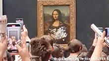 Visitors take pictures and video of the painting Mona Lisa after cake was smeared on the protective glass at the Lourve Museum in Paris, France May 29, 2022 in this screen grab obtained from a social media video. Twitter/@klevisl007/via REUTERS THIS IMAGE HAS BEEN SUPPLIED BY A THIRD PARTY. MANDATORY CREDIT.
