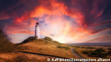 Leuchtturm auf der Insel Hiddensee bei Sonnenuntergang mit dramatischem Himmel.