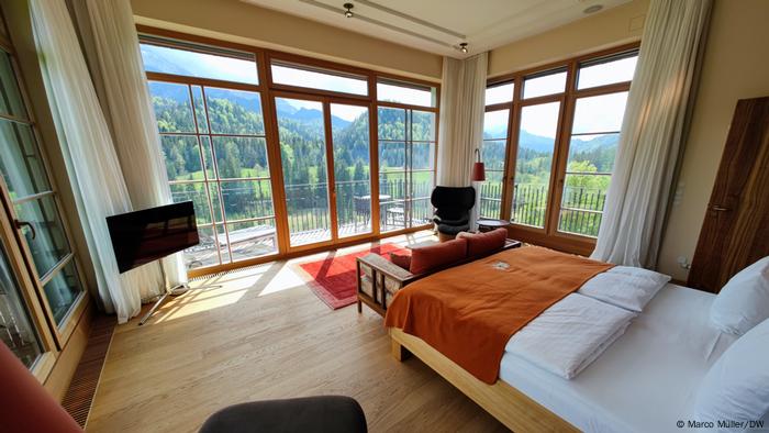 A bedroom of the Summit Suite with a view of the bed and views out the windows on three sides of the room